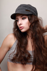 Sexy young woman with long hair in trendy cap. Hipster