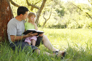 young father with his little daughter reads the Bible
