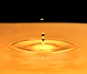 a drop of water falls in a golden water. macro