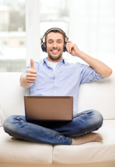 smiling man with laptop and headphones at home