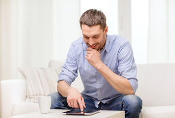 Obraz premium smiling man working with tablet pc at home