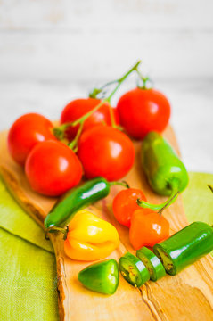 Assorted pepper and tomatoes on wooden background