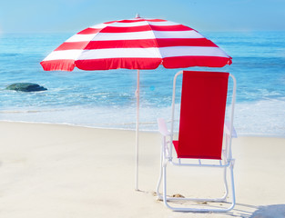 Beach umbrella and chair by the ocean