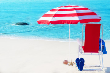 Beach umbrella and chair by the ocean