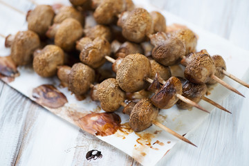 Champignon kebabs, wooden background, horizontal shot