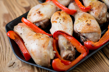 Frying pan with grilled chicken legs and sliced red bell pepper