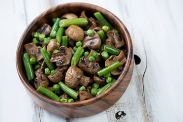 Roasted champignons with vegetables in a wooden bowl
