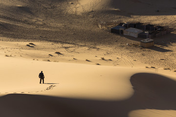 Fototapeta premium Man walking on dunes in desert