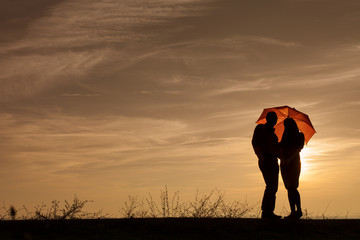 Silhouette of pregnant woman and a man in the sunset