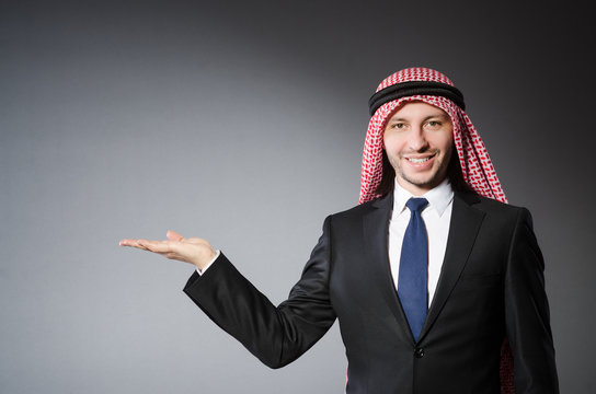 Arab businessman holding hands against grey background