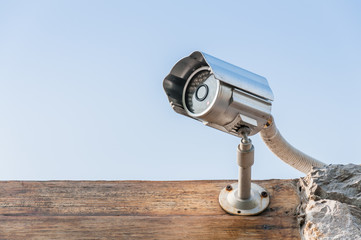 CCTV camera on wooden wall against sky