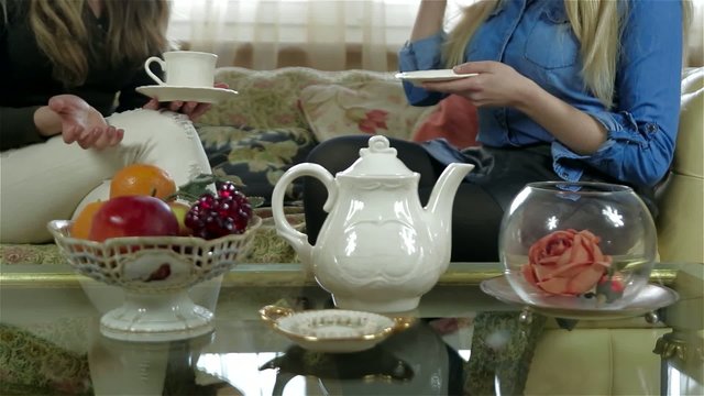 Elegant tea set on the table, two girlfriends on the background