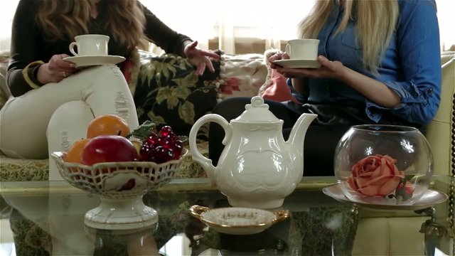 Elegant tea set on the table, female friends on the background