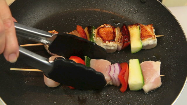 Fresh chicken kababs in a fry pan and turning them