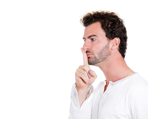 Serious man asking to be quiet, finger on lips gesture
