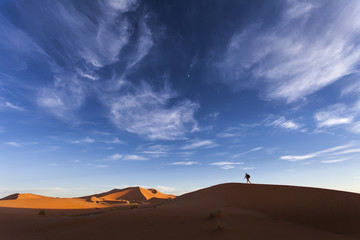 Adventure man walking on dunes in desert Sahara, Morocco, Africa