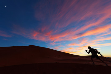 Photographers playing on dunes of desert Sahara at sunset, Moroc