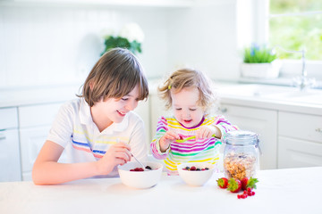 Obraz na płótnie Canvas Teenager boy, his toddler sister having fruit for at breakfast