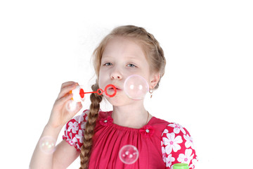 little girl 8 years old blowing soap bubbles