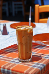 Glass of ice cold frappe coffee with a drinking straw