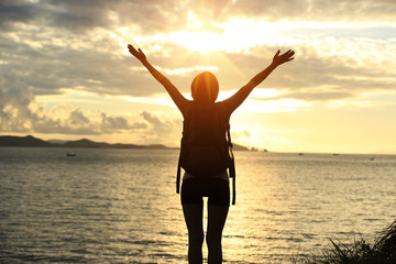 Fototapeta premium cheering hiking woman open arms at sunrise seaside