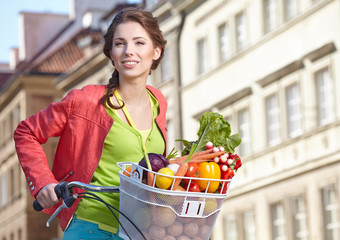 Pretty spring  woman with bicycle and groceries in old town stre