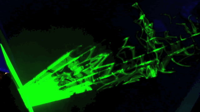 Green laser light flashing on a dark background.