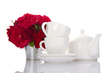 White crockery for tea and a bouquet of roses
