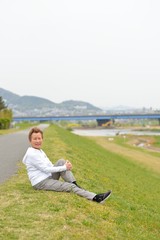 Naklejka na ściany i meble 芝生の上に座って準備運動をする高齢のアジア人女性