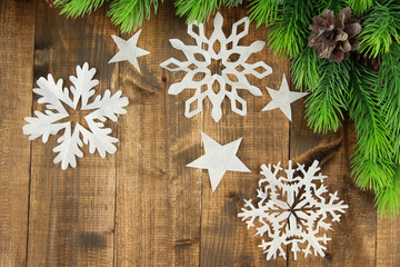 Beautiful paper snowflakes with fir branch on wooden background