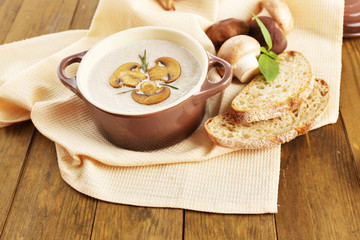 Mushroom soup in pot, on wooden background