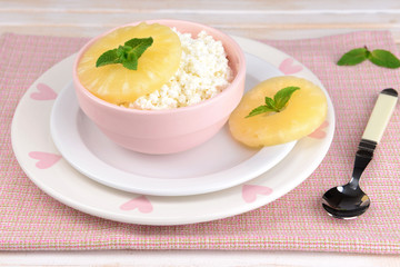 Bowl of tasty cottage cheese with pineapple on wooden table