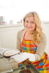 Woman pulling pie from oven