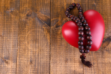 Heart with rosary beads on wooden background