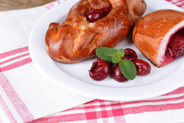 Fresh baked pasties with cherry on plate on table close-up