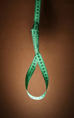 Tape measure noose on brown background - diet concept