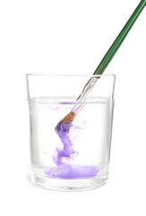 Brush with color paint in glass of water, isolated on white