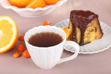 Piece of delicious cake  with oranges on tablecloth close-up
