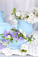 Beautiful spring flowers in cups on wooden table