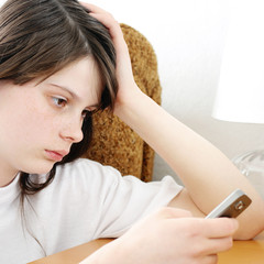 Naklejka premium Sad Teenage Girl with Cellphone