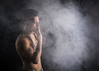 Shirtless young man smoking cigarette with a lot of smoke around