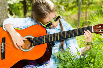 Pretty little girl playing a guitar. Spring time