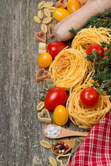pasta, tomatoes and spices on wooden background, top view
