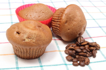 Fresh baked muffins and coffee grains on colorful cloth