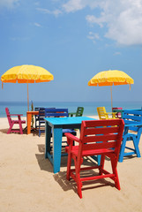 Colorful chair and table with yellow umbrella on the beach
