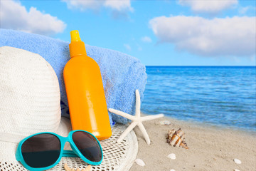 Straw hat, sunglasses, towel and starfish on sand beach.