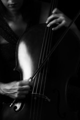 Beautiful brunette playing cello with selective light in red dre