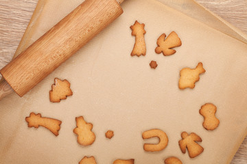 Rolling pin and gingerbread cookies on cooking paper