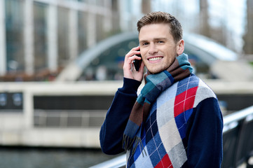 Handsome man using mobile at bridge railing