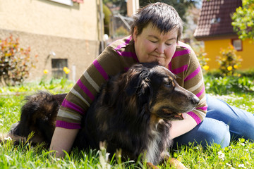 Portrait einer behinderten Frau mit Hund auf einer Wiese